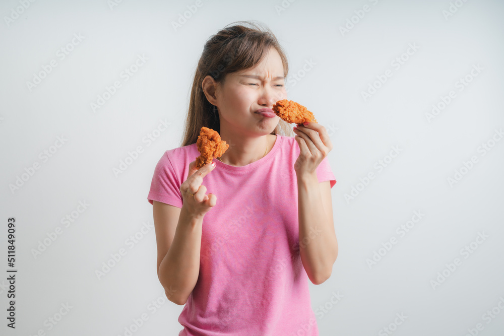 Young asian woman holding and eating fries chicken on white background Young asian woman holding and eating fries chicken on white background