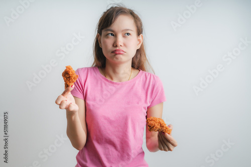 Young asian woman holding and eating fries chicken on white background