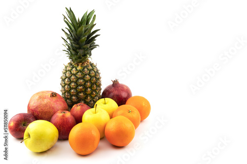 Beautiful fruits on a white isolated background. Pineapple  pomegranate  apples  oranges. Summer season.