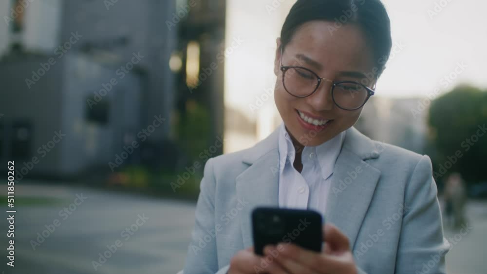 Beautiful business woman walking use mobile phone on street near business center. Happy smiling female look around at sunlight. Slow motion Beautiful business woman walking use mobile phone on street near business center. Happy smiling female look around at sunlight. Slow motion
