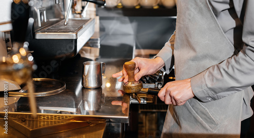 Close-up of a masked bartista preparing delicious delicious coffee at the bar in a coffee shop. The work of restaurants and cafes during the pandemic.