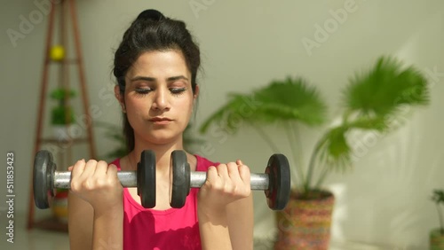 Strong fitness Young Indian woman doing arm workout with dumbbells in living room.Sport and fitness.Asian female doing exercise with dubbell at home gym.healthy concept. photo