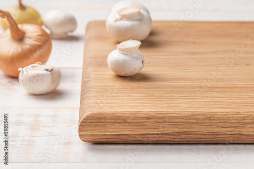 square wooden cutting board with mushrooms and spices on a white background. mockup with copy space for text, side view, close-up