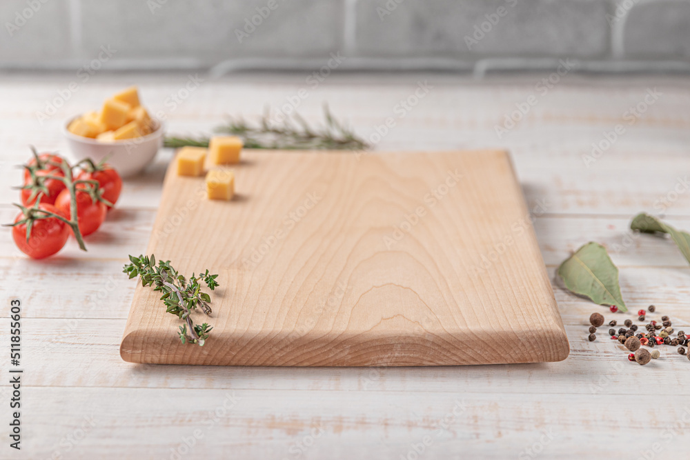 square wooden cutting board with cherry tomatoes, cheese and spices on a white background. mockup with copy space for text, side view