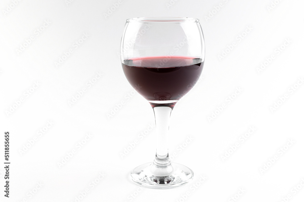 A wide glass transparent glass with red wine, half full, on a white background, isolated glassware with a drink A wide glass transparent glass with red wine, half full, on a white background, isolated glassware with a drink