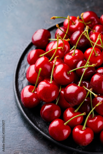 Red cherry on a black plate. Sweet cherries on a dark background. Freshly picked delicious red berries