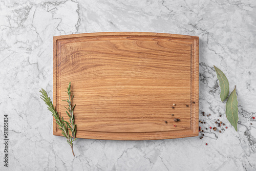 square wooden cutting board with edging. thyme and spices on a white marble background. mockup with copy space for text, top view photo