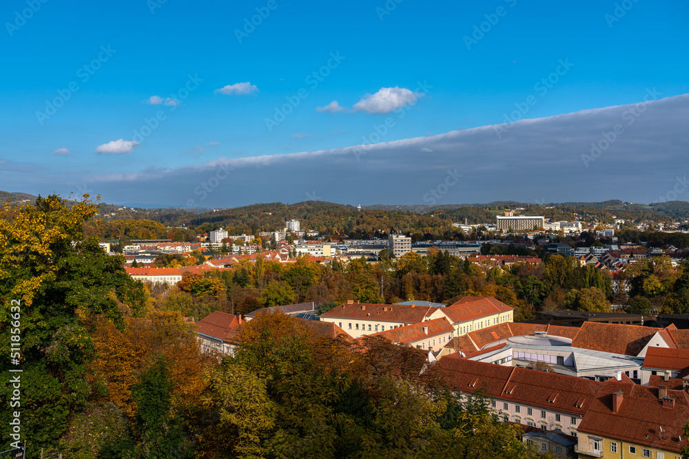 Aerial panorama view of Graz cityscape from Schlossberg in northeast of LKH hospital and Mariatrost direction on a sunny day in autumn, with blue sky cloud and colorful trees, Graz, Styria, Austria