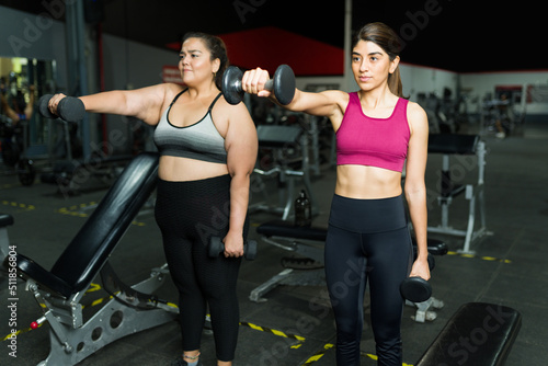 Latin trainer and obese woman using weights © AntonioDiaz