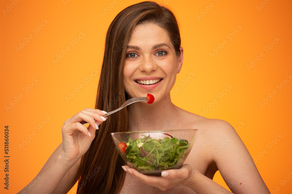 Happy woman eating salad, girl with bared shoulders and long hair isolated portrait on orange yellow background. Happy woman eating salad, girl with bared shoulders and long hair isolated portrait on orange yellow background.