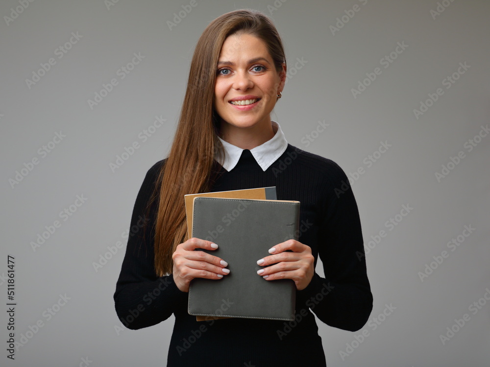 Happy female teacher or student in black business suit with white collar holding book, isolated portrait of businesswoman. Happy female teacher or student in black business suit with white collar holding book, isolated portrait of businesswoman.
