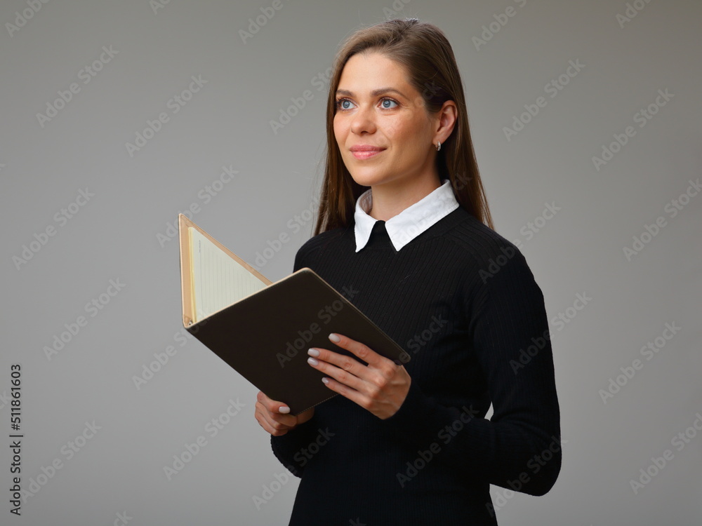 Smiling woman teacher or student in black business suit with white collar and long hair holding open book and looking away, isolated portrait of businesswoman. Smiling woman teacher or student in black business suit with white collar and long hair holding open book and looking away, isolated portrait of businesswoman.