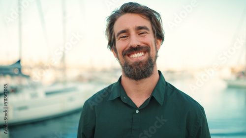 Obraz na plátně Close-up portrait of a smiling man with a beard on the embankment, on a yacht background
