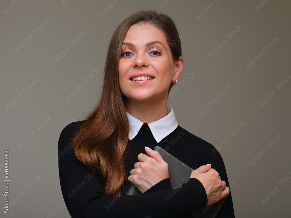 Smiling woman teacher in black suit with white collar holding book and arms crossed, isolated female portrait. Smiling woman teacher in black suit with white collar holding book and arms crossed, isolated female portrait.