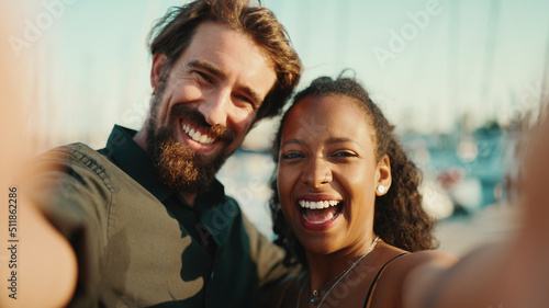 Close up portrait of happy man and smiling woman doing stream on smartphone. Close-up, joyful young interracial couple communicating via video call using mobile phone