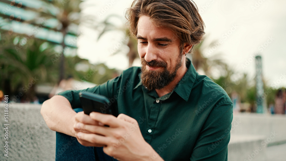 Close-up portrait of a man with a beard recording a voice message on the embankment background. Closeup of a young hipster male using a mobile phone Close-up portrait of a man with a beard recording a voice message on the embankment background. Closeup of a young hipster male using a mobile phone
