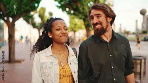 Closeup, man and woman walking smiling holding hands. Close-up of a young interracial couple in love going on a city street