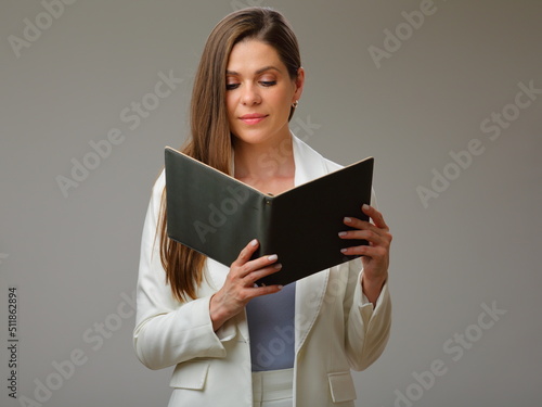 Serious woman in white suit reading book, studio isolated female portrait.