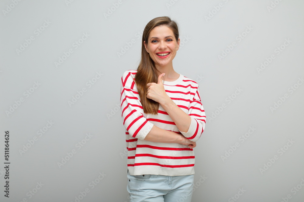 Smiling woman standing with thumb up, isolated female studio portrait, girl in white sweater with red stripes.. Smiling woman standing with thumb up, isolated female studio portrait, girl in white sweater with red stripes..