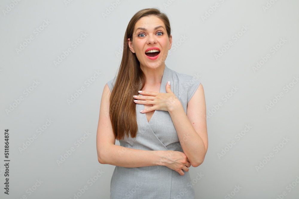 Happy amazed smiling woman holding hand on chest wearing gray business dress isolated portrait. Happy amazed smiling woman holding hand on chest wearing gray business dress isolated portrait.