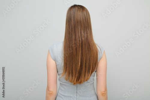 Woman in business dress standing back, female portrait with long hair. Back view. Rear view.