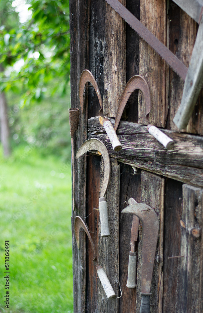 Old rusty gardening tools hanging on the wall