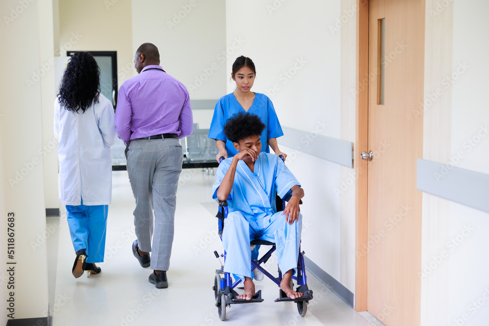 young nurse pushing young black man patient on a wheelchair in the hospital corridor to the patient room young nurse pushing young black man patient on a wheelchair in the hospital corridor to the patient room