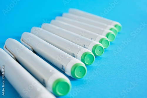 a lot of insulin syringe pens for diabetes treatment on blue background