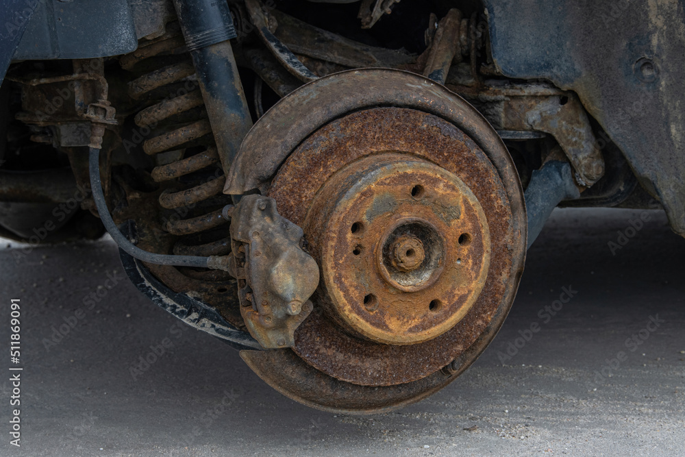 Close-up of the suspension and brake drum of an old rusty car with the wheel removed