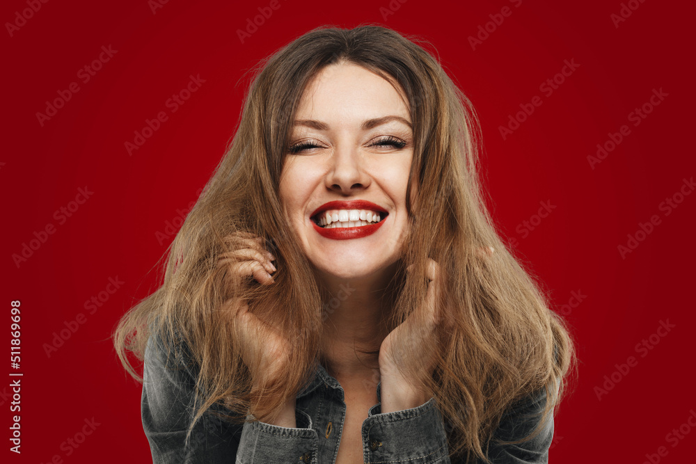 Woman with good sense of humor wearing red lipstick laughing out loud at joke with closed eyes