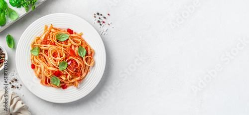 Italian linguini pasta with tomato sauce and fresh basil on a gray background with space to copy. Vegetarian food. View from above.