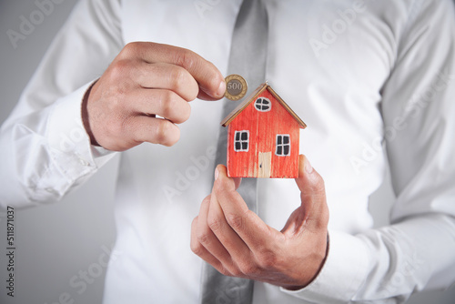 Businessman holding house model and coin.