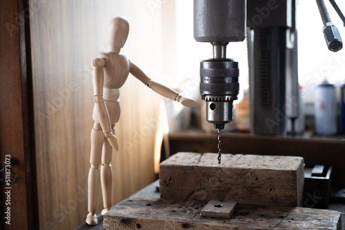 Close up of a wooden mannequin near a drill in the construction, rag doll