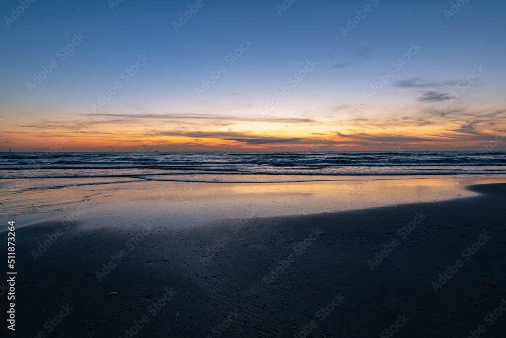 Twilight sky over the North Sea during the period of the shortest nights. Beautiful reflections of colours in the wet sand. Twilight sky over the North Sea during the period of the shortest nights. Beautiful reflections of colours in the wet sand.