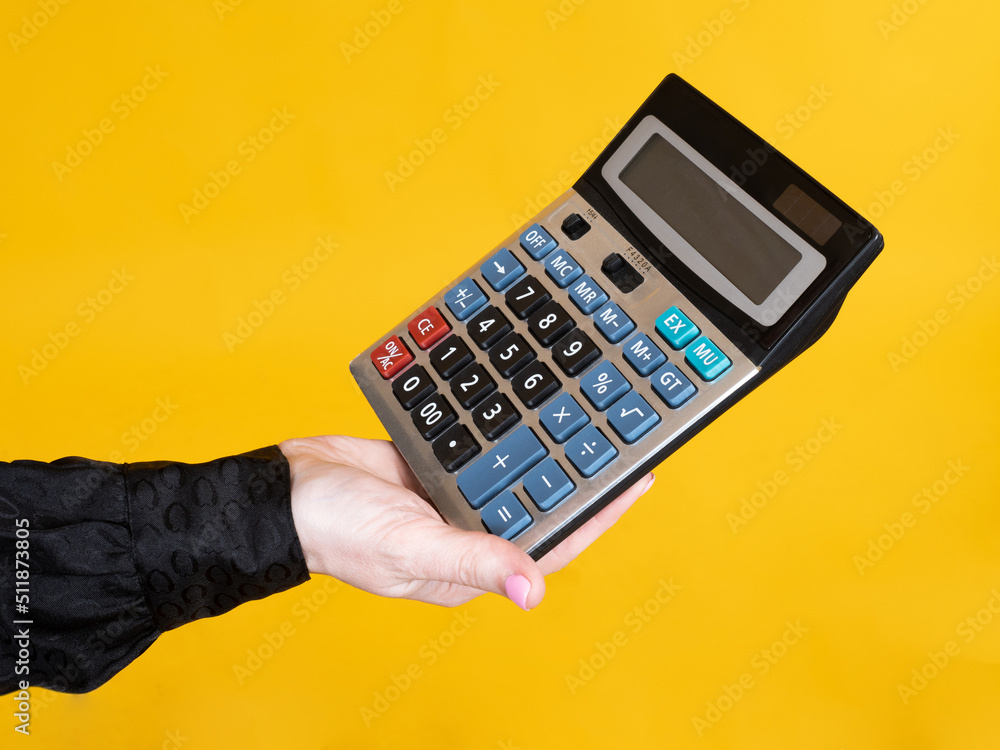 Accountant's hand holding calculator. Accountant demonstrates device for accounting. Electronic calculator on yellow. Woman's hand with calculator. Concept of accounting and auditing services Accountant's hand holding calculator. Accountant demonstrates device for accounting. Electronic calculator on yellow. Woman's hand with calculator. Concept of accounting and auditing services