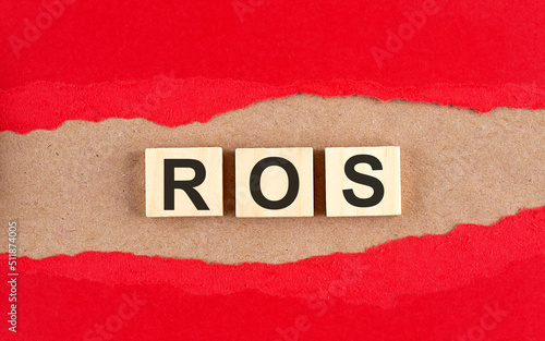 ROS word on wooden cubes on red torn paper , financial concept background