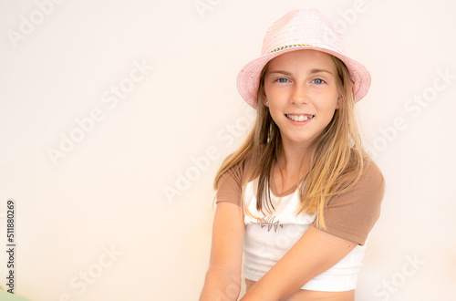 Portrait of beautiful smiling blond kid girl wearing hat outdoors
