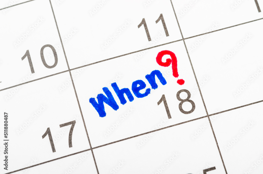 Hand writing When and Question mark sign on desk calendar page. Hand writing When and Question mark sign on desk calendar page.
