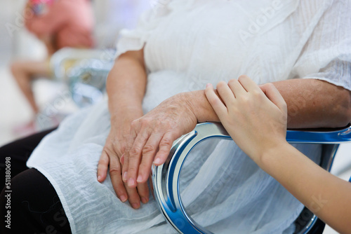 Close up hand holding together. Young asian doctor in blue uniform and senior woman holding hands together. Positive Asian woman caregiver helping patient.