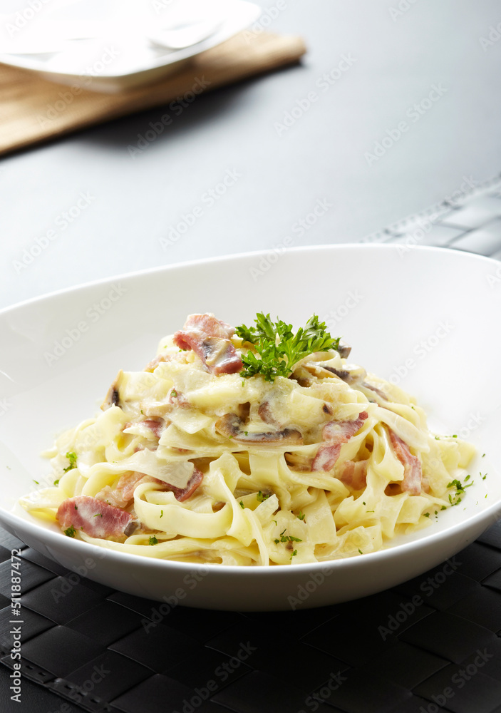 Close-up of pasta with cheese and bacon on wooden table