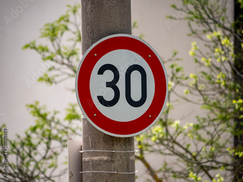 30 speed limit sign on a solid light post. German speed limit in a city. Rules for the road users. The traffic speed must not be faster as 30 kilometers per hour. The road sign restricts the freedom. photo