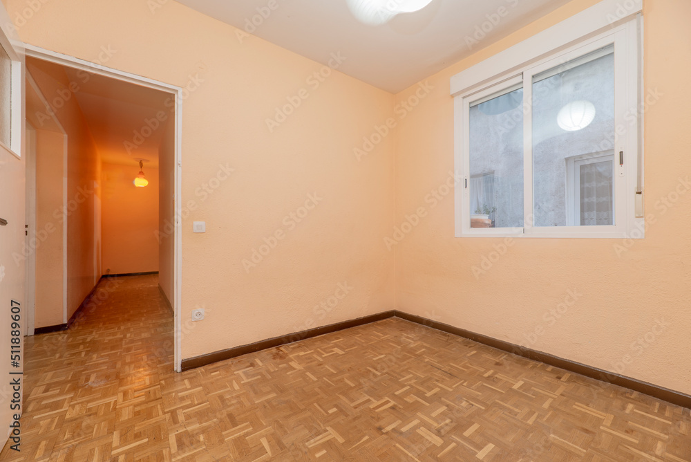 Empty room with white aluminum window, peach painted walls and oak parquet Empty room with white aluminum window, peach painted walls and oak parquet