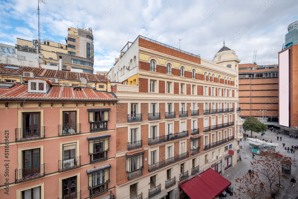 Facades of old urban residential buildings with clay roofs and small attic windows near Plaza del Callao in Madrid