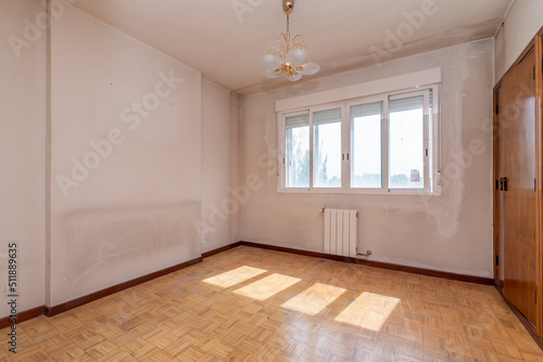 Empty room with fitted wardrobes on one side and double aluminum windows