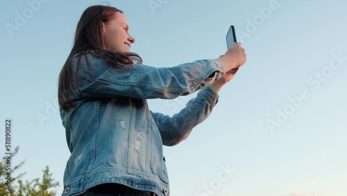Serene blogger woman hold smartphone and look at rural scene share content creator vlog, vlogger girl reel live stream post photo and relax enjoy tour with dawn sunlight blue sky. Wunderlust concept photo