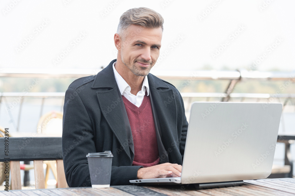 Happy man employee working online in laptop drinking coffee in outdoor cafe Happy man employee working online in laptop drinking coffee in outdoor cafe