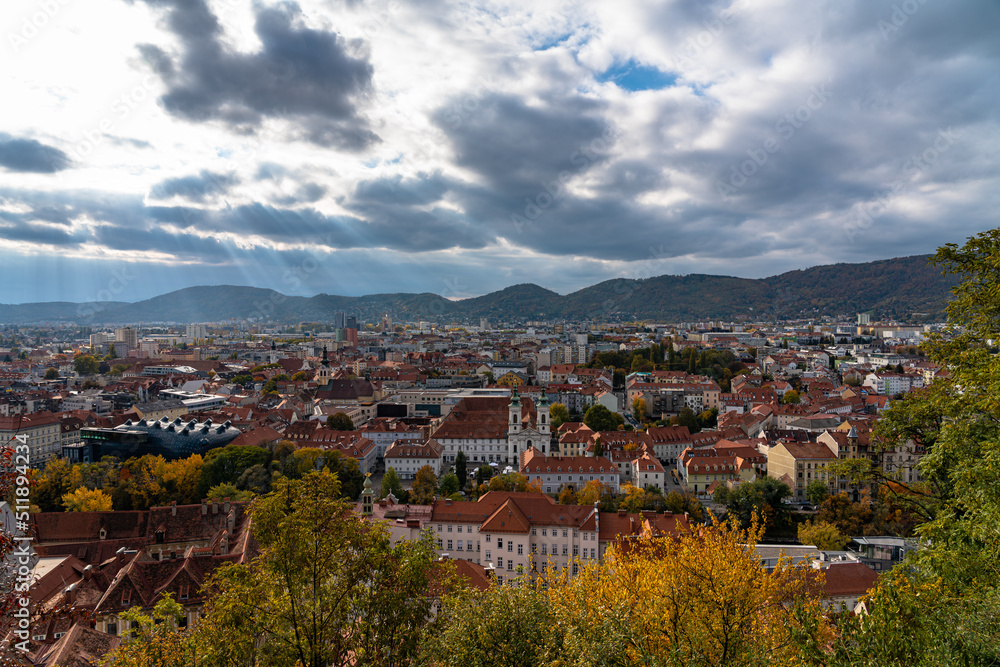 Aerial panorama view of Graz city old town Lend in west bank of Mur river with Kunsthaus and Mariahilfkirche from Schlossberg on autumn day with blue sky cloud, colorful trees, Graz, Styria, Austria