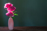 pink peonies in pink vase  on green background