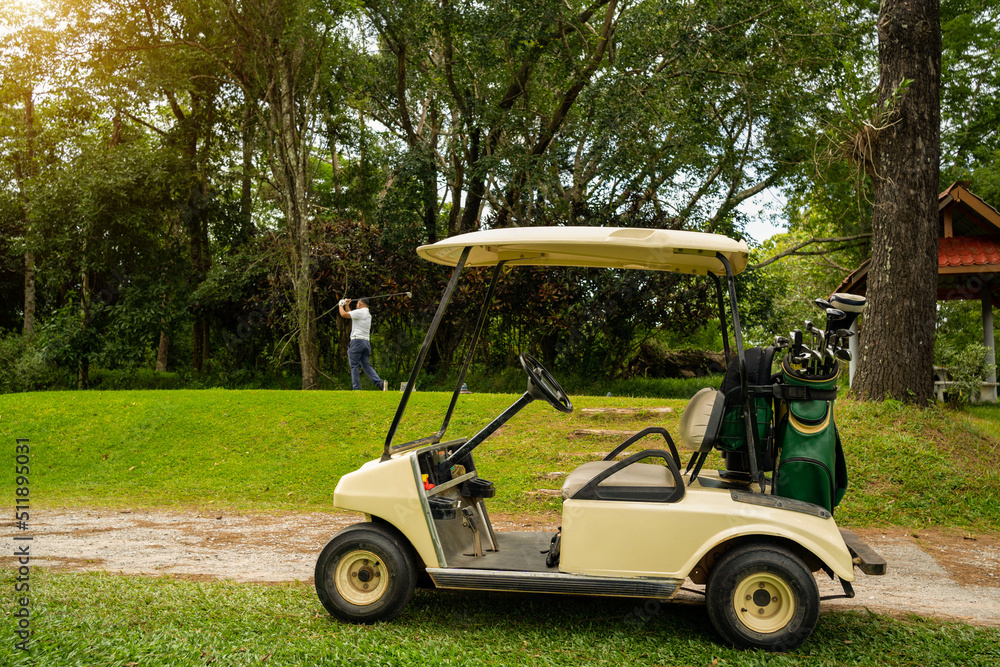 Golf cart or car club and blurred golfer swing golf ball to green in golf course