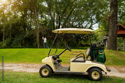 Golf cart or car club and blurred golfer swing golf ball to green in golf course
